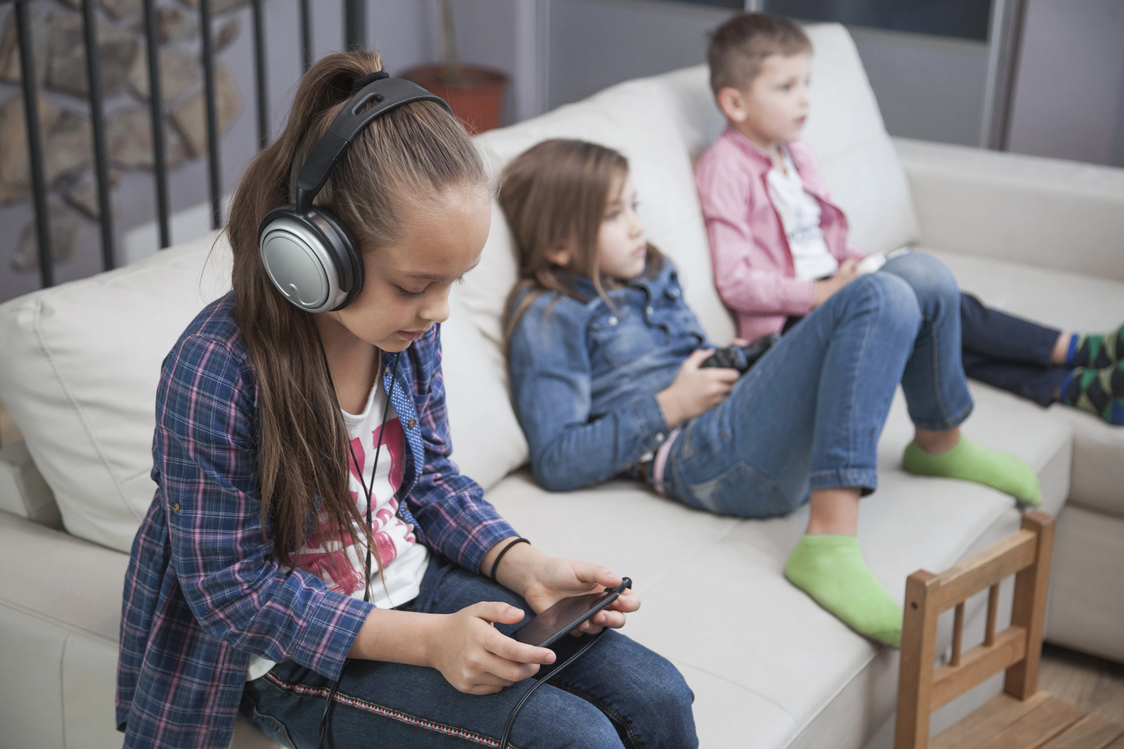 girl-using-smartphone-near-siblings.jpg
